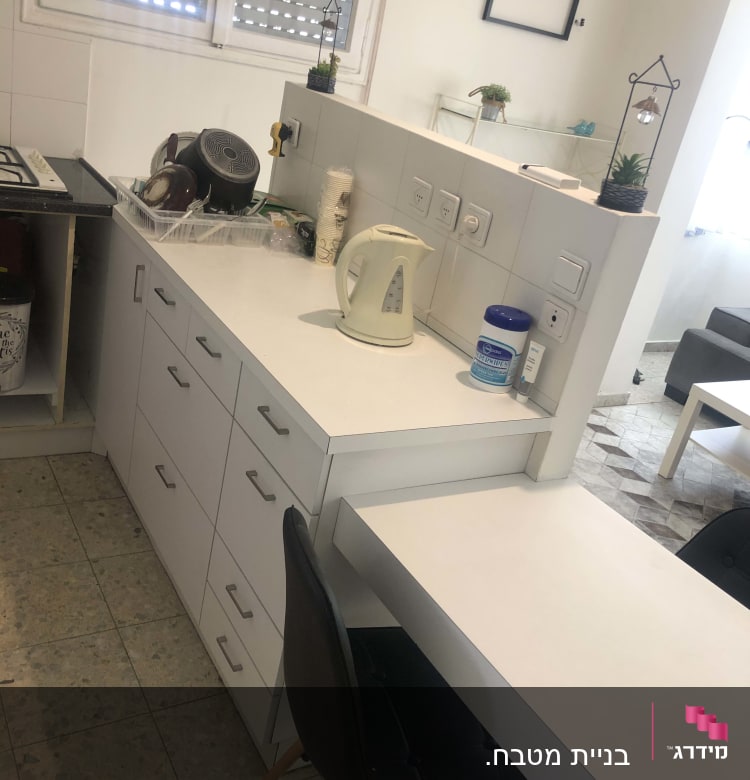 קומקום חשמלי על השיש במטבח עם כלים בכיור